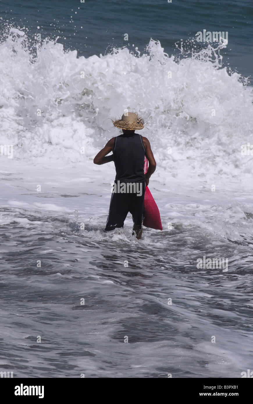 Uomo di ciottoli di raccolta come il surf va in e out,kusamba ,bali , Repubblica di Indonesia Foto Stock
