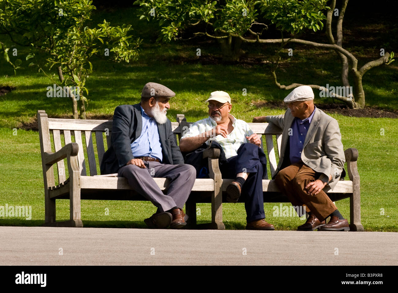 Regent's Park Gardens , scena di tre uomini molto vecchi seduti su un banco di lavoro avente dibattito animato e godersi il sole estivo Foto Stock