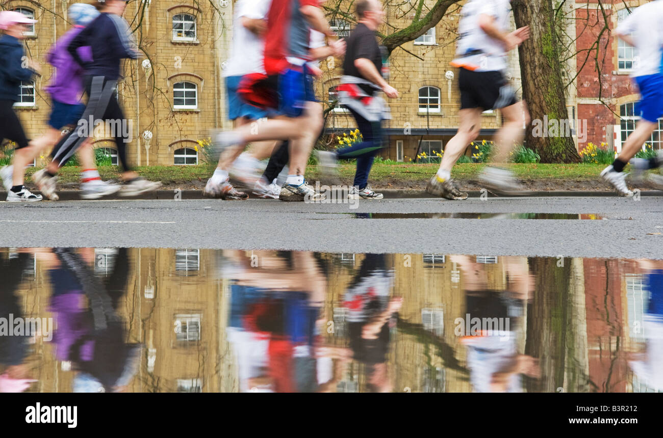 Corridori della maratona riflessa nella pozzanghera Foto Stock