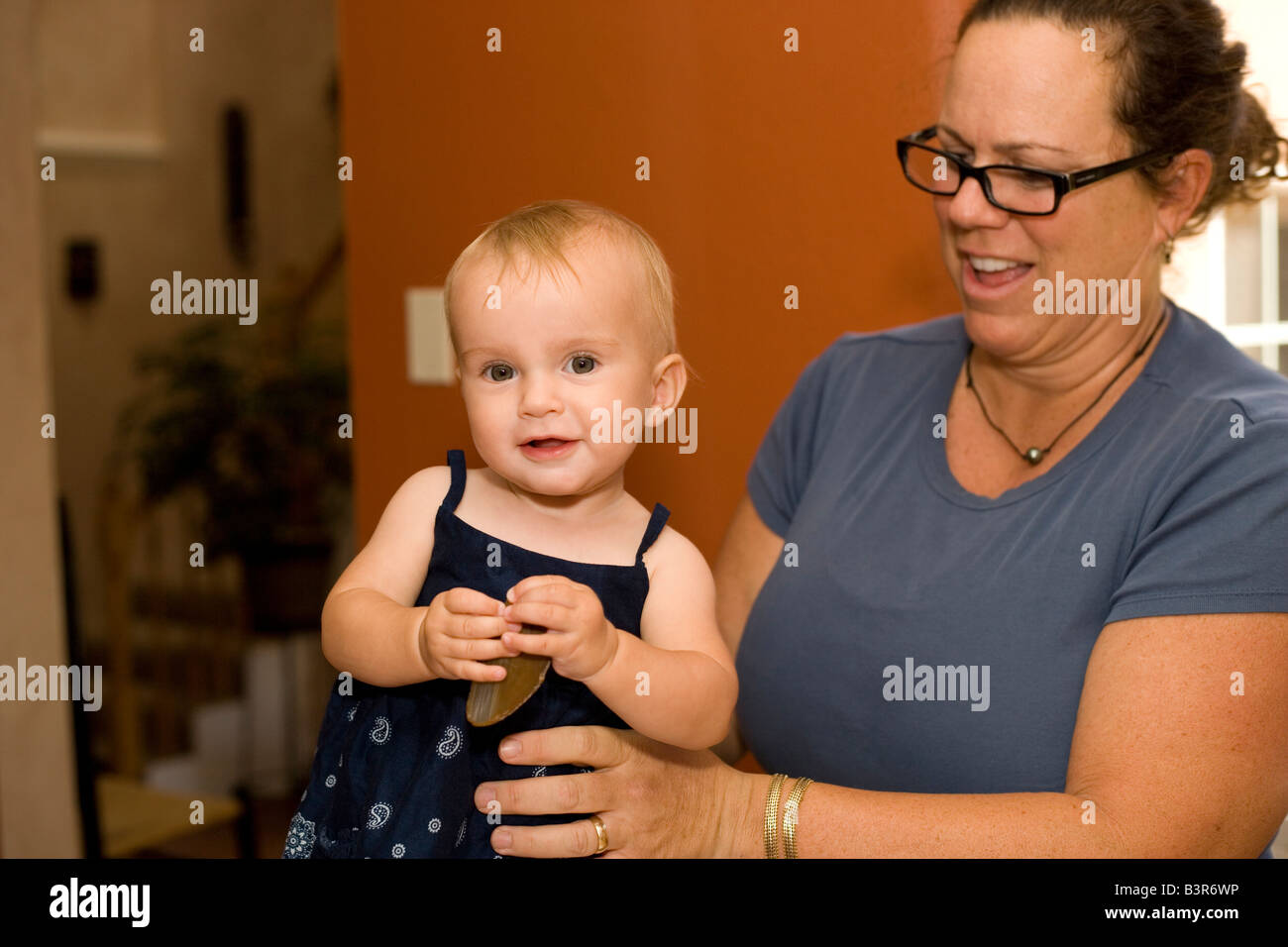 Madre tenendo la sua bambina come bambino utilizza il linguaggio dei segni per chiedere 'more' Foto Stock