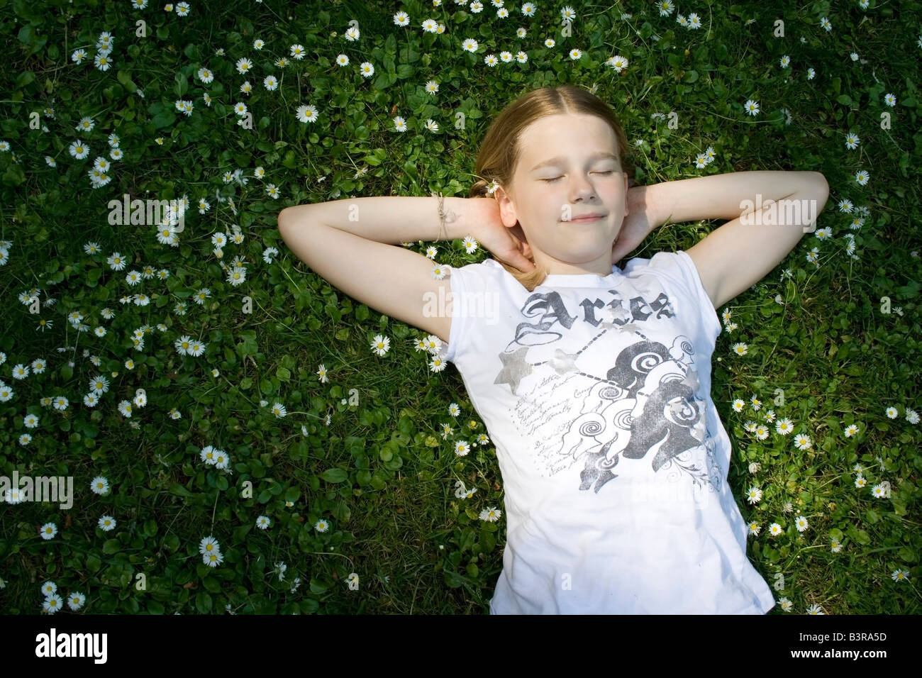 Giovane ragazza distesa in erba pieno di margherite Foto Stock