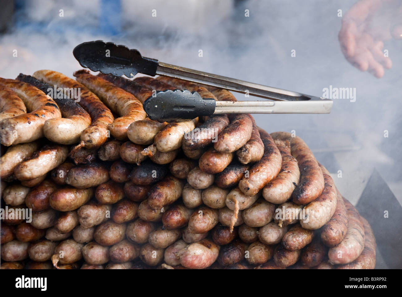 Barneville, Normandia, Francia. Salsicce fresche alla griglia in una stalla nel mercato settimanale Foto Stock