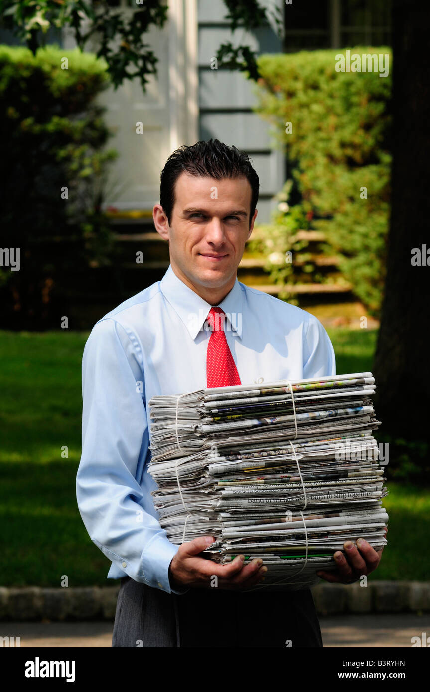 Coscienza ambientale uomo che porta una pila di giornali per essere riciclata Foto Stock