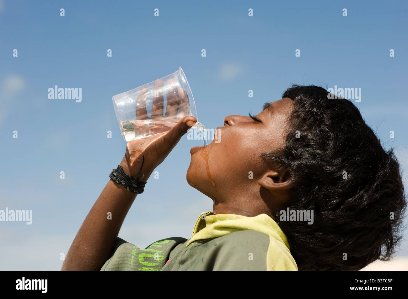 Ragazzo indiano acqua potabile dalla tazza di plastica. India Foto Stock