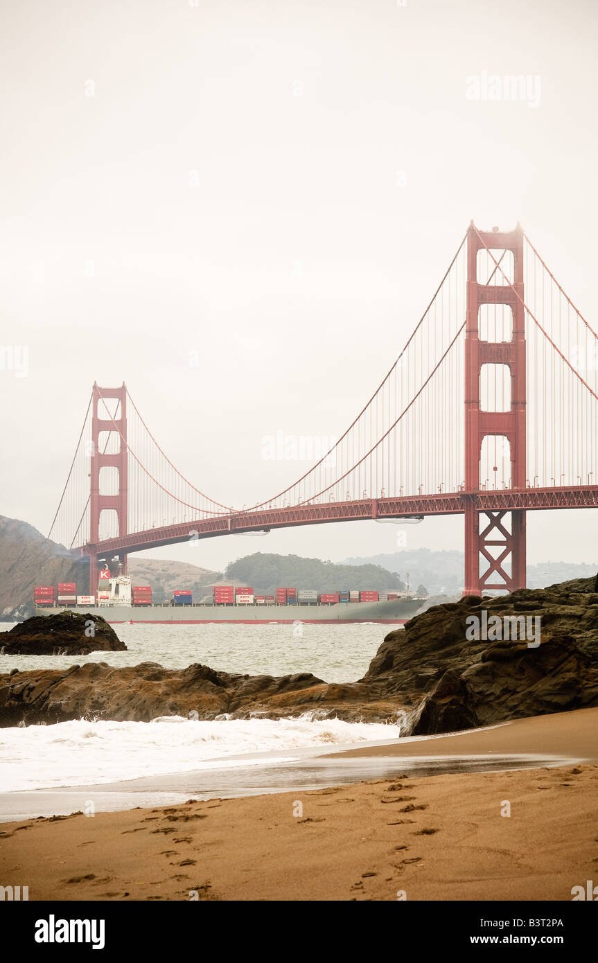 Vista verticale del Golden Gate Bridge visto da Baker Beach con nave portacontainer passando al di sotto di Foto Stock