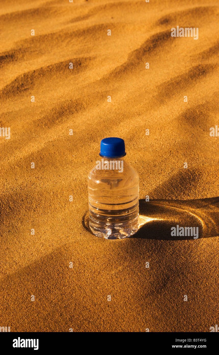 Una bottiglia di acqua in un deserto Foto Stock
