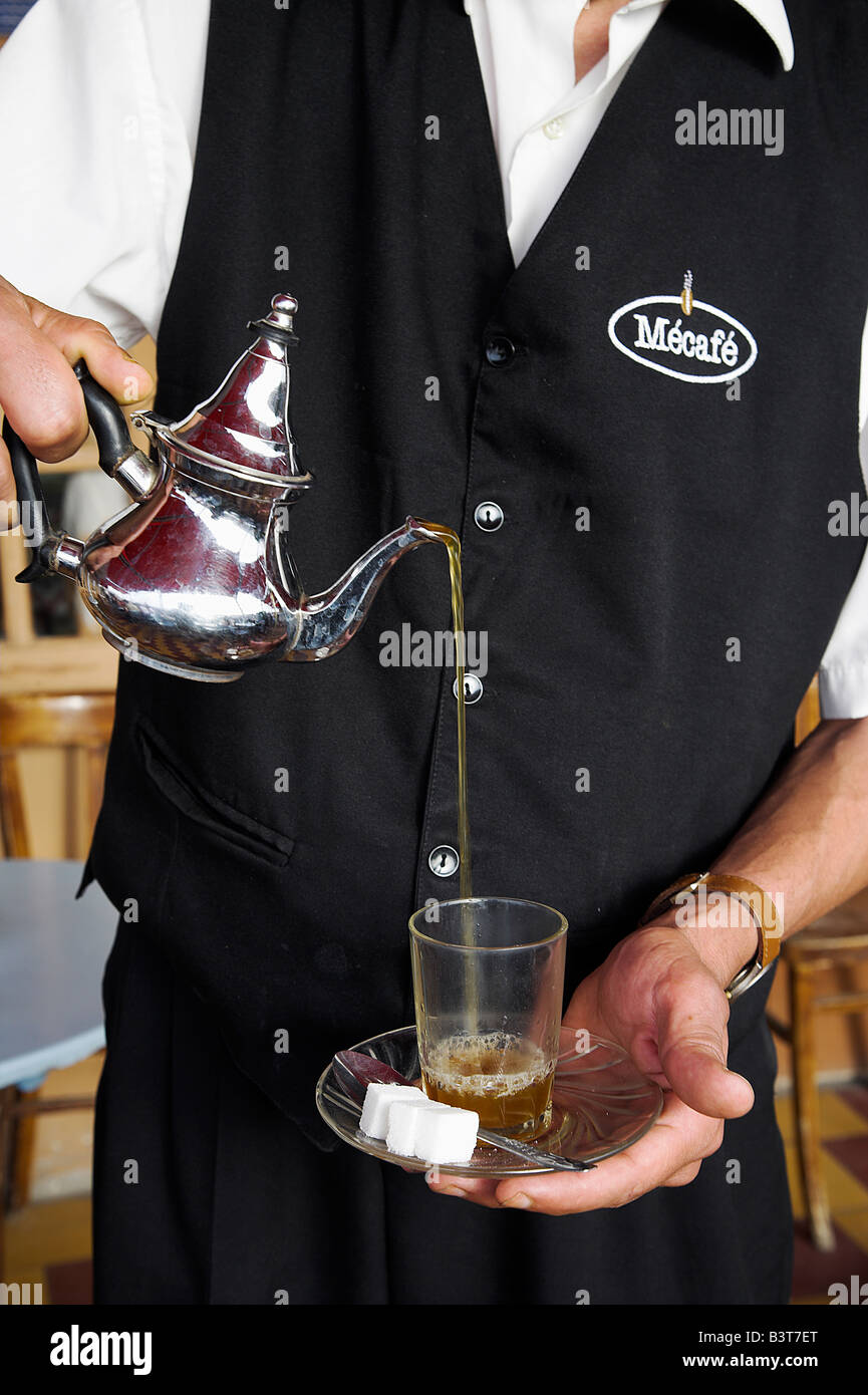 Il Marocco, Tangeri. Un cameriere versa un bicchiere di tè alla menta del Marocco drink preferito. Foto Stock