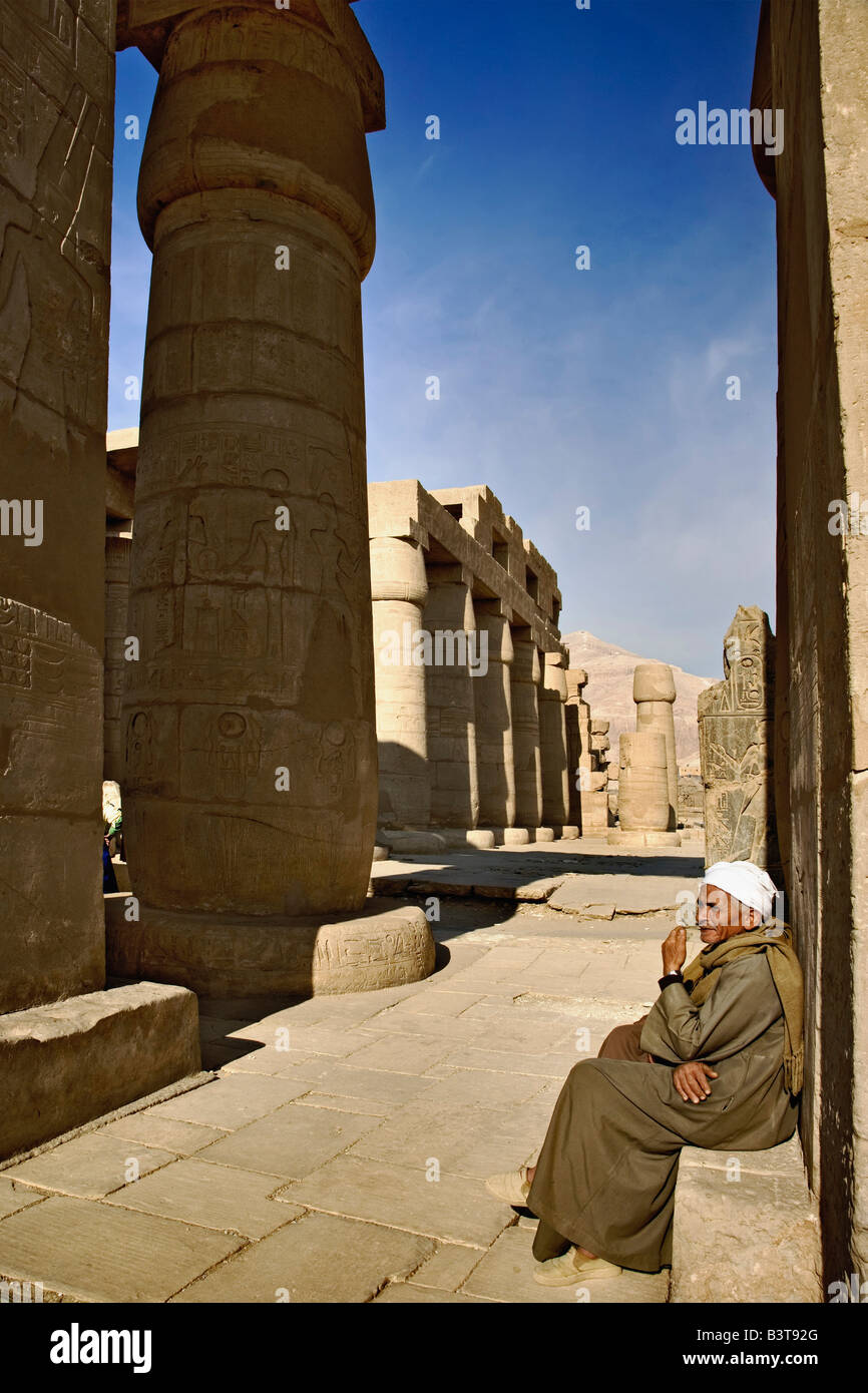 Egyptian uomo seduto accanto a Hypostyle Hall all'Ramessuem sulla riva occidentale di Luxor in Egitto. Costruito da Ramesse II. Foto Stock