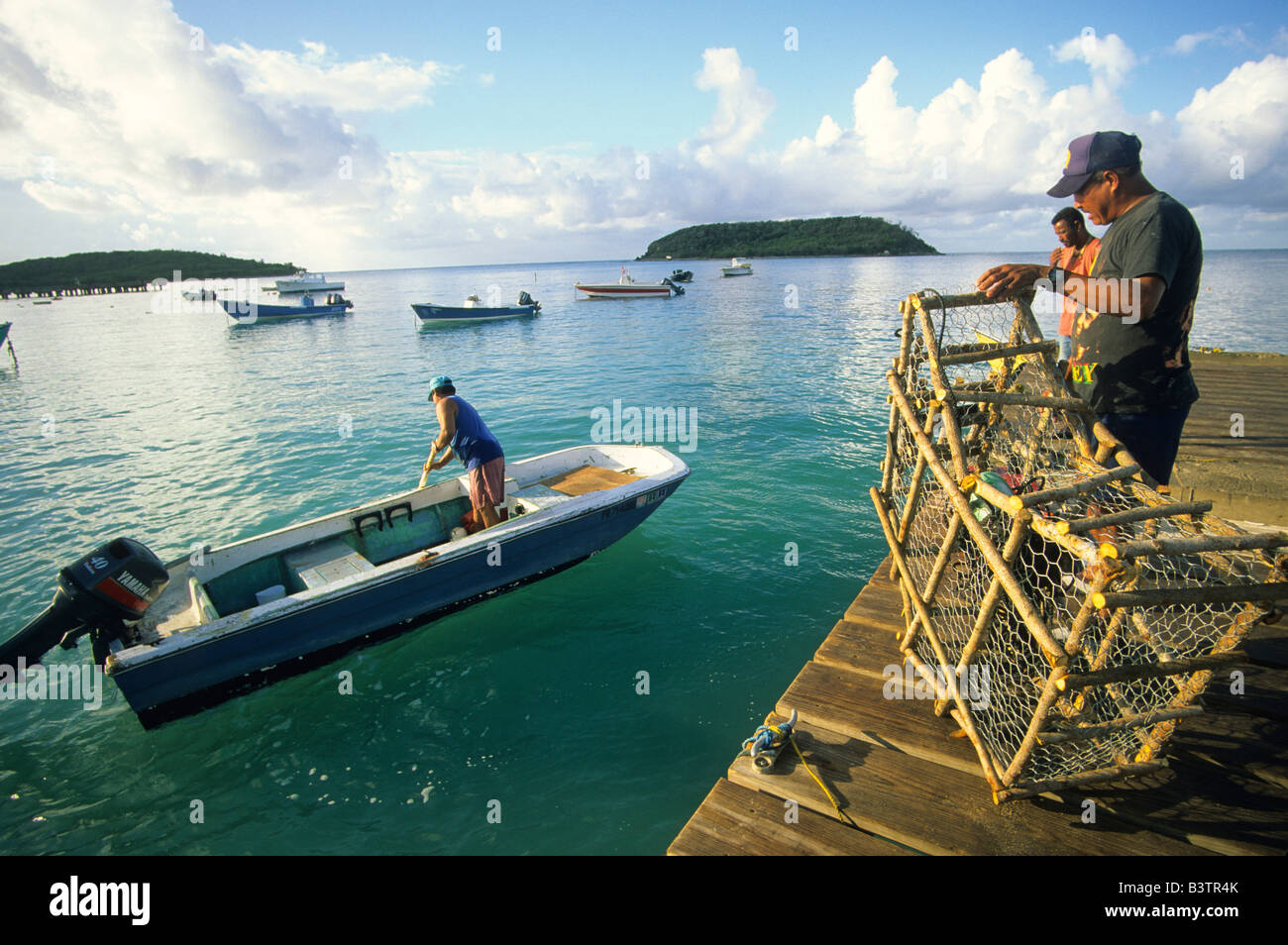 I pescatori holding trappole di pesce sulla Esperanza harbour dock con barche di pescatori sull'isola di Vieques Foto Stock