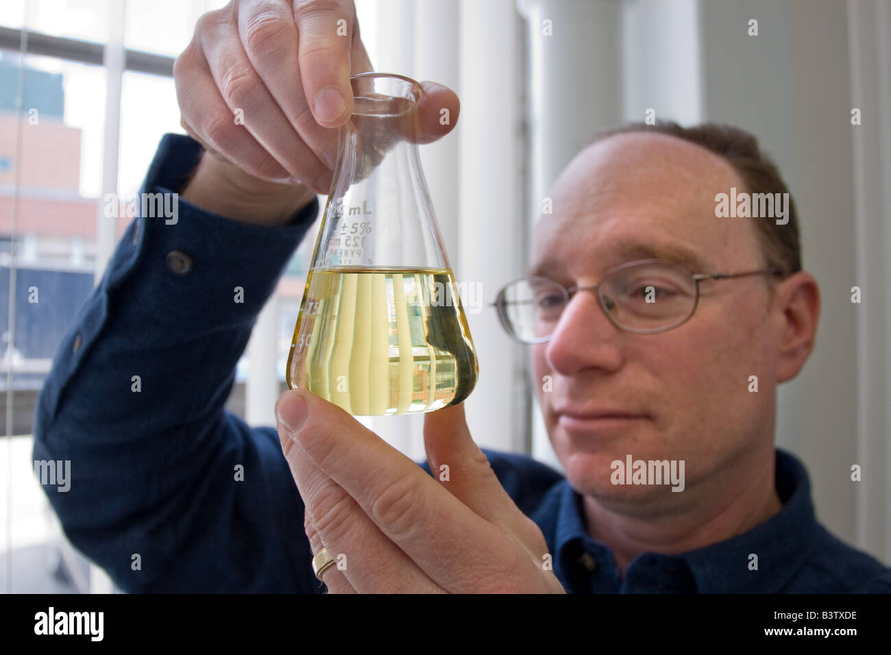 Uno scienziato con un bicchiere di bio-diesel realizzato da olio di cottura Foto Stock