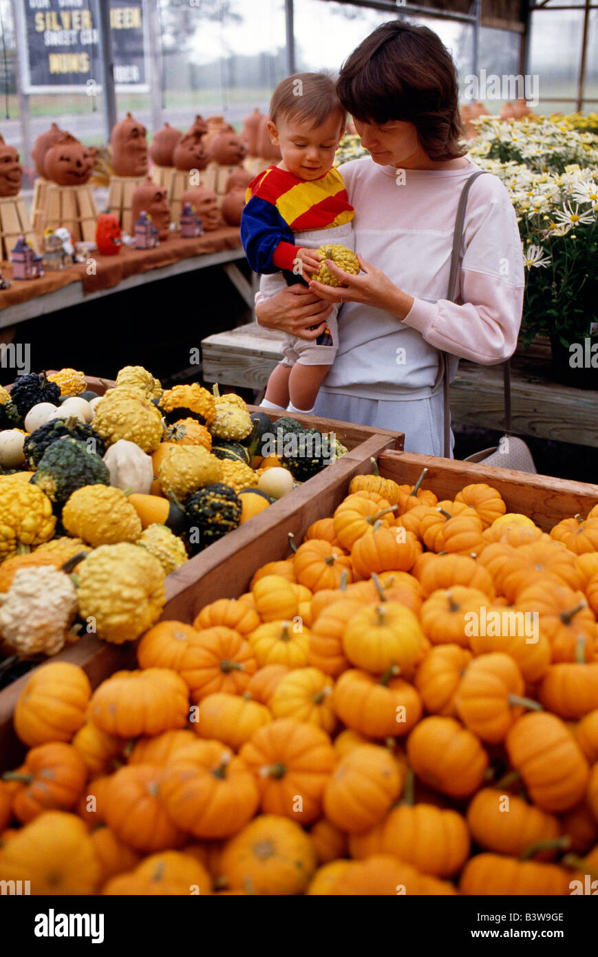 La madre e il bambino acquisto di zucche & zucche di un mercato agricolo. Foto Stock