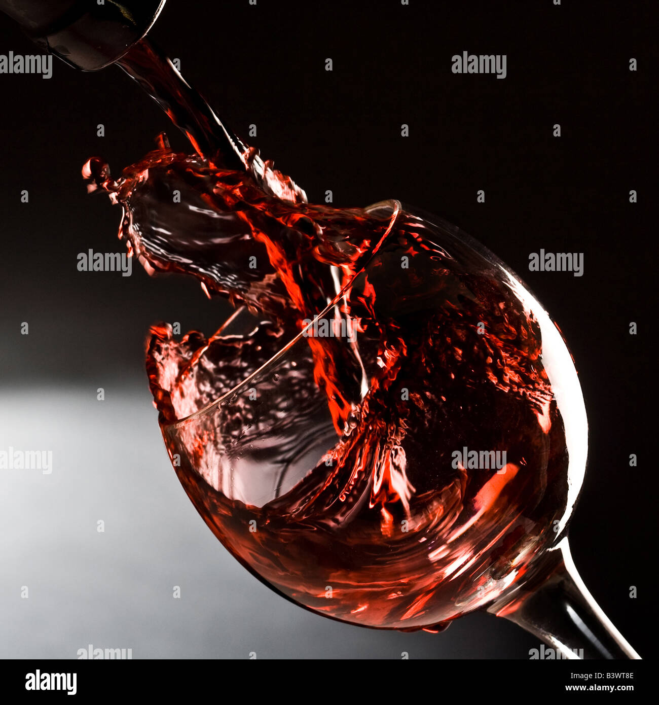 Vino rosso versando in giù in un bicchiere da vino Foto Stock