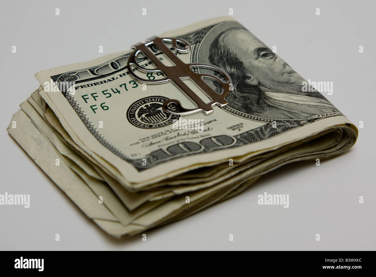 Una pila di fogli piegati 100 dollari in soldi di argento clip con il simbolo di denaro. Foto Stock