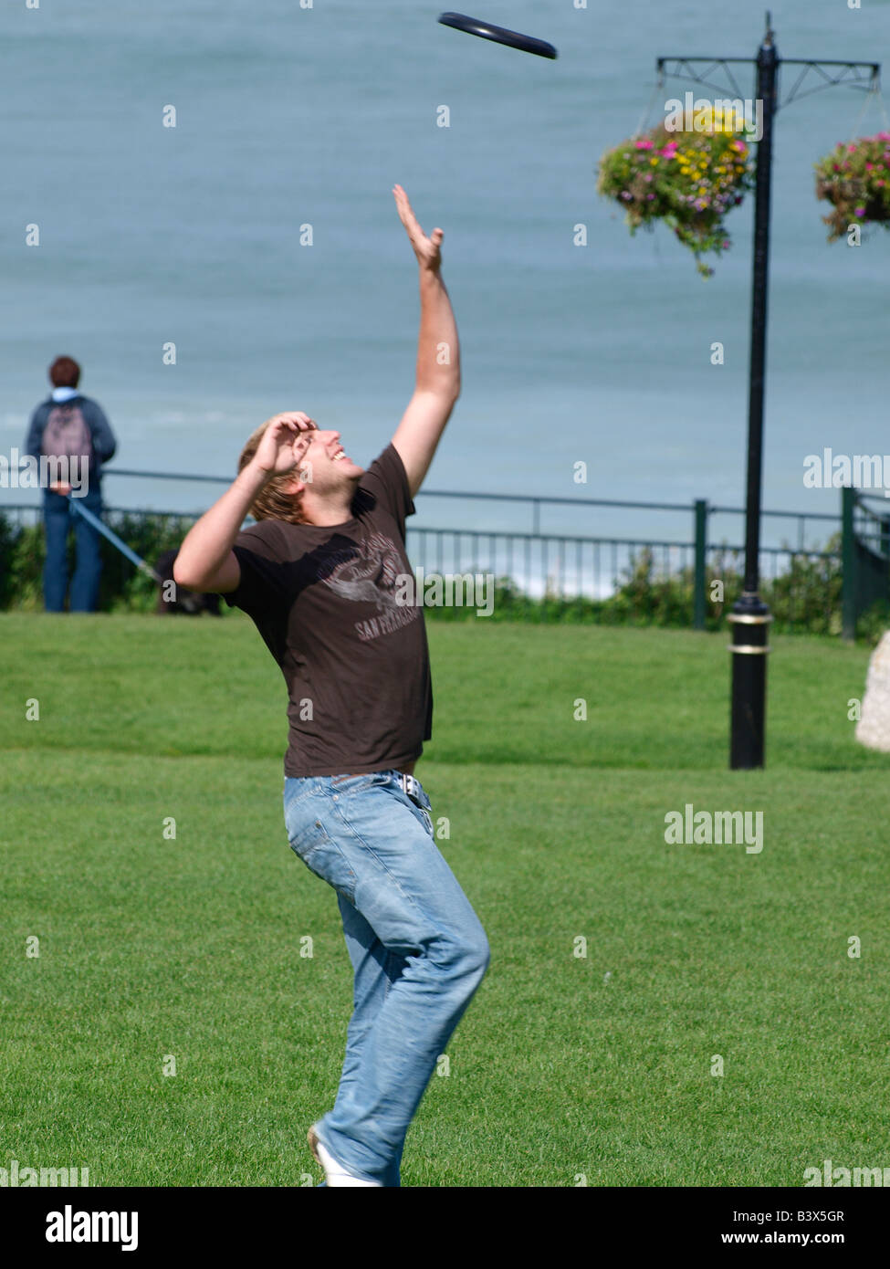 20's uomo jumping per la cattura di un frisbee Foto Stock