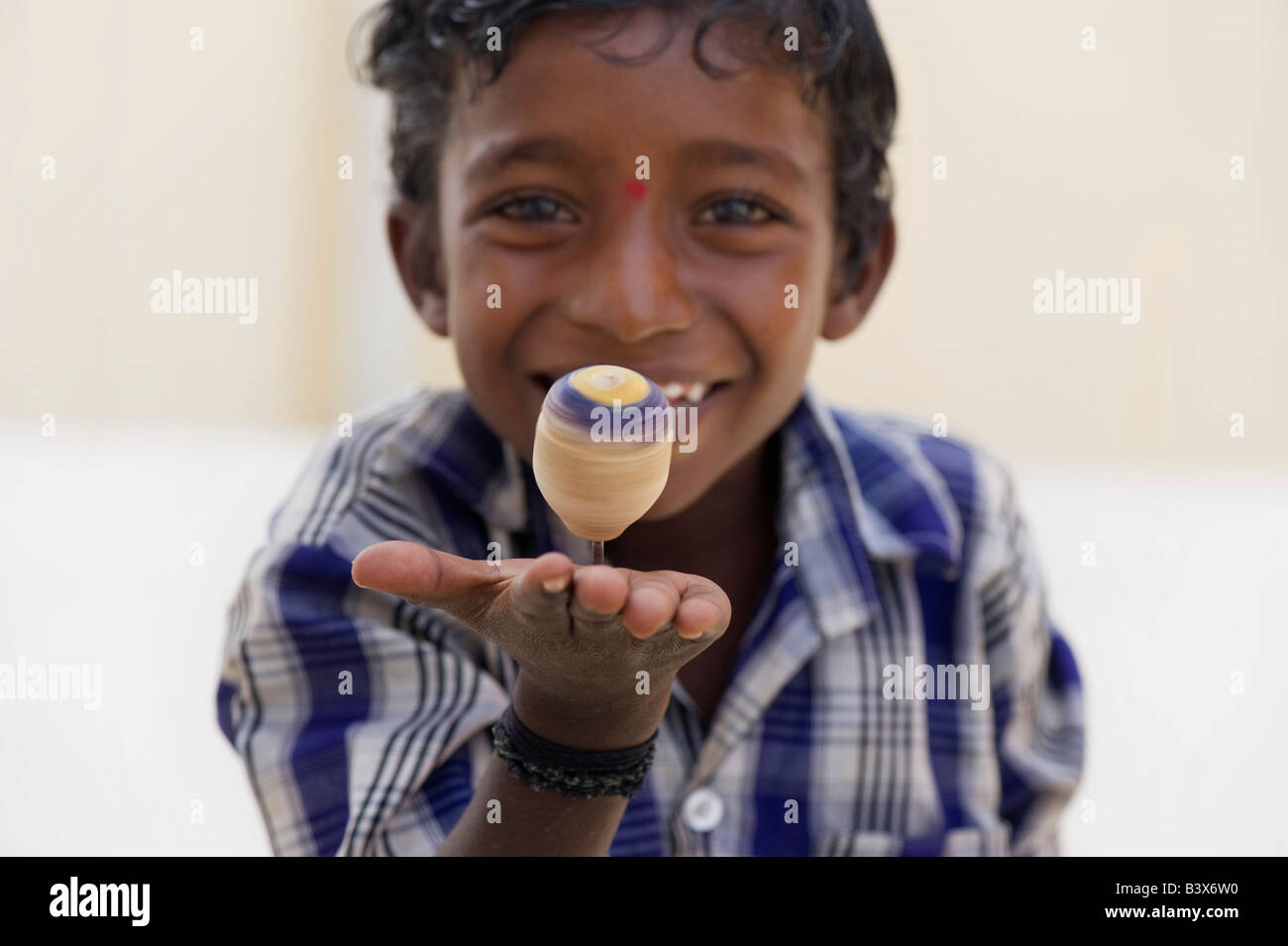 Ragazzo indiano sorridente giocando con la filatura in legno top giocattolo. India Foto Stock