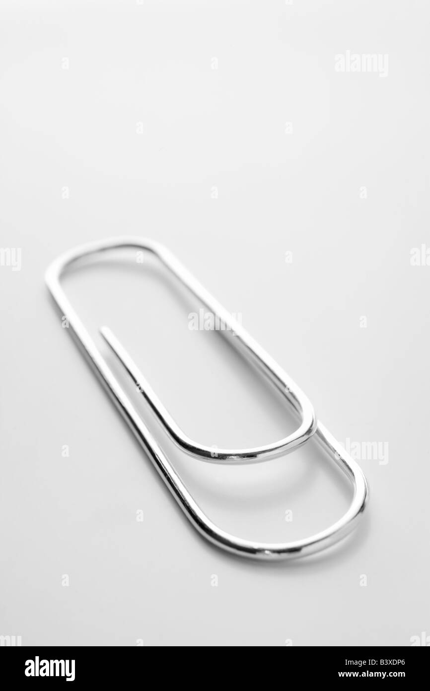 Close Up di argento a forma di graffetta contro uno sfondo bianco Foto Stock