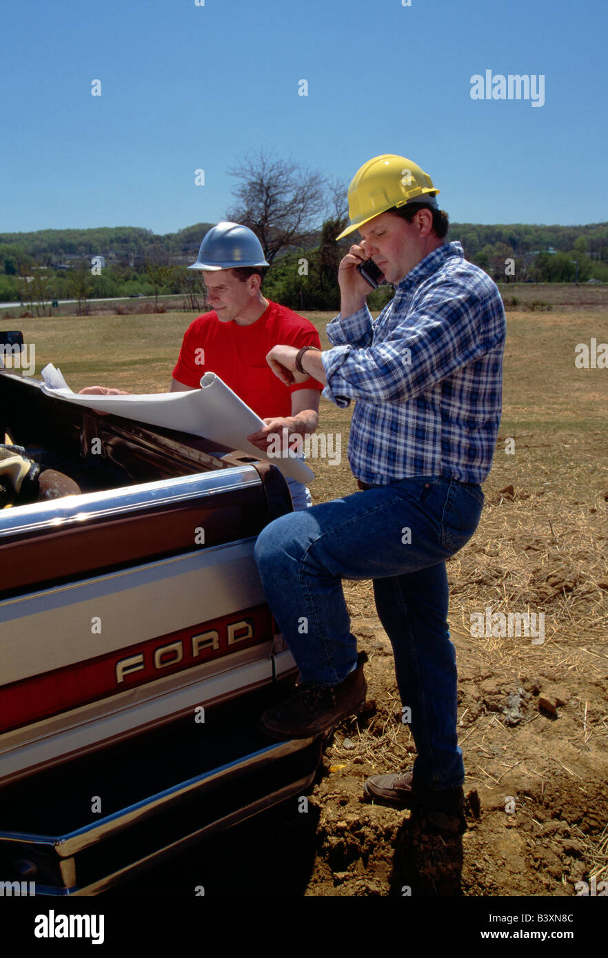 Due lavoratori rivedendo disegni su un sito in costruzione Foto Stock