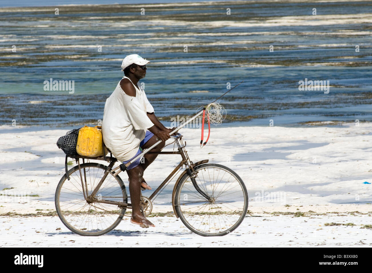 Pescatore con arpione su una bicicletta il ritorno a casa di BWE Juu Zanzibar Tanzania Foto Stock