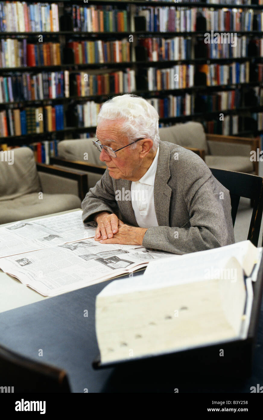 Anziano gentiluomo leggendo il giornale presso la biblioteca pubblica in Burlingame, California, Stati Uniti d'America Foto Stock