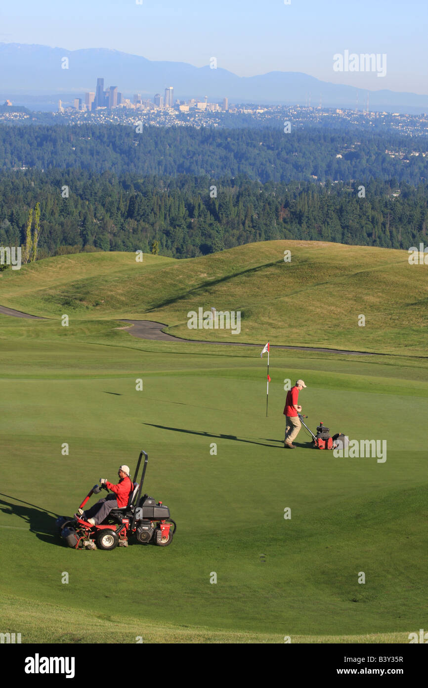 Nelle prime ore del mattino, con la skyline di Seattle in background, i Verdi equipaggio preparare il Newcastle Golf Club per giocare. Foto Stock