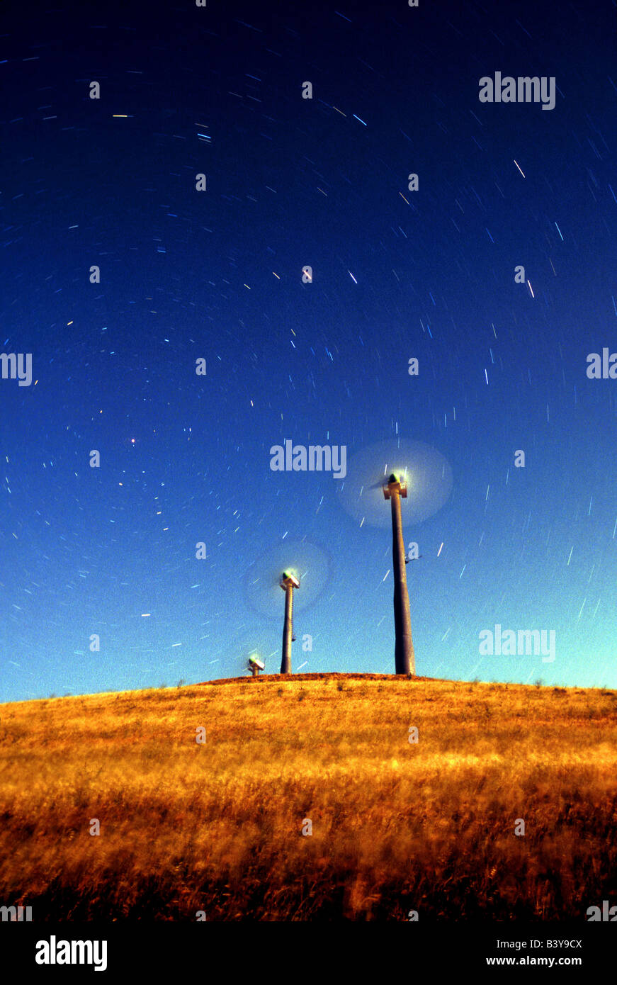 Startrails appaiono essere soffiata da turbine eoliche sotto una luna piena. Foto Stock