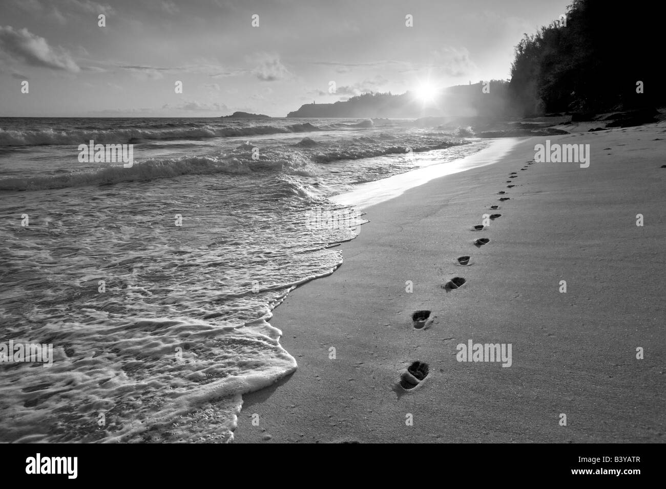 Alba alla spiaggia segreta con impronte nella sabbia Kauai Hawaii Foto Stock