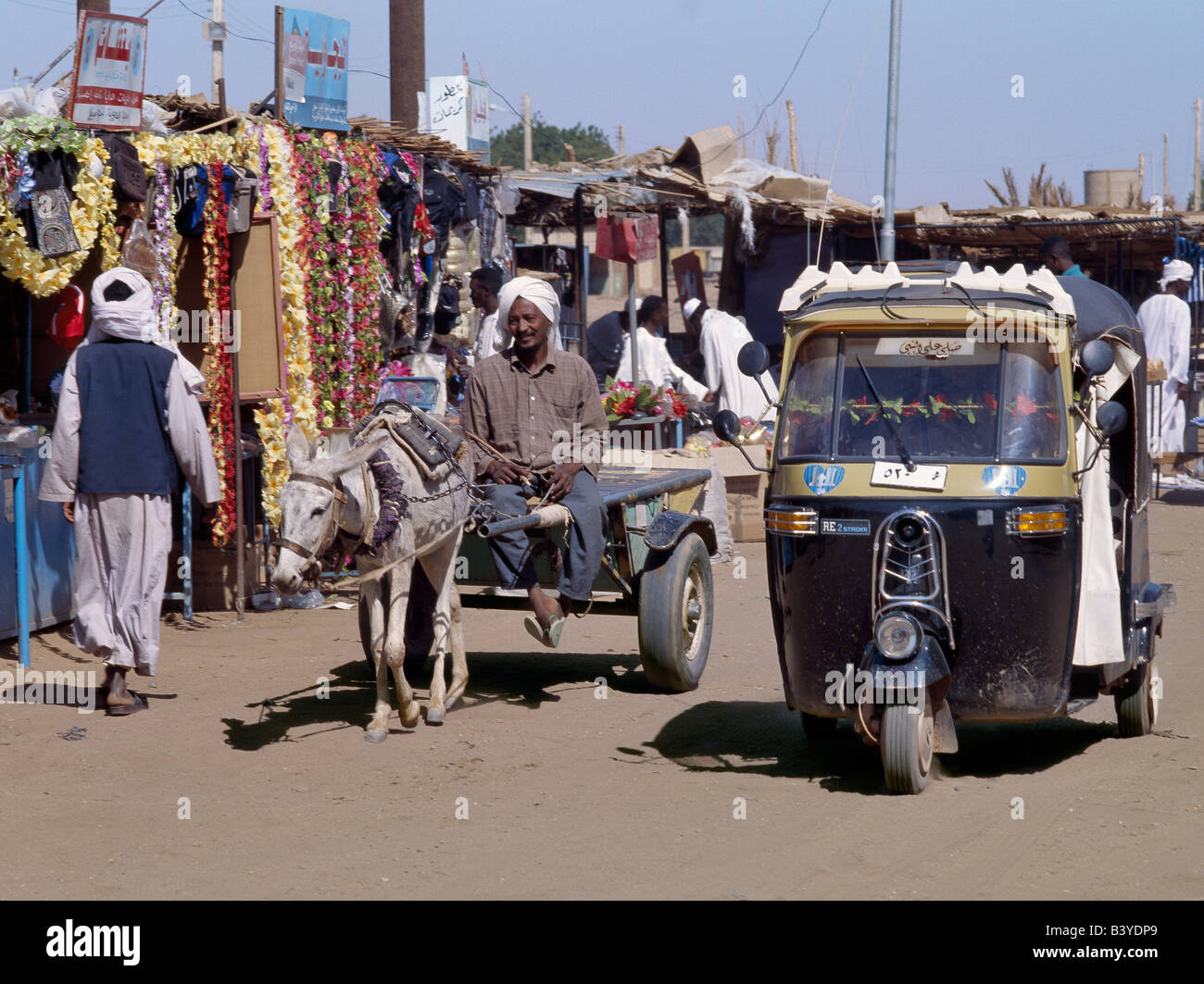 Sudan, Karima. Antichi e moderni mezzi di trasporto fili le polverose strade del mercato importante città di Karima. Indiano-realizzato tre ruote di Bajaj i taxi sono diventati popolari forme di moderni mezzi di trasporto nelle città in tutto il Sudan. Foto Stock