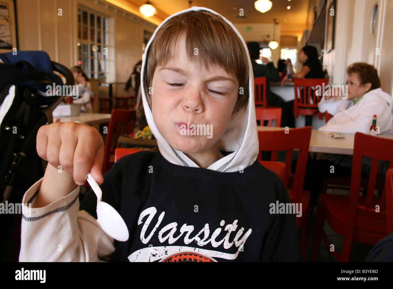 6 anno vecchio ragazzo rendere divertente l'espressione durante la degustazione salato clam chowder zuppa Foto Stock