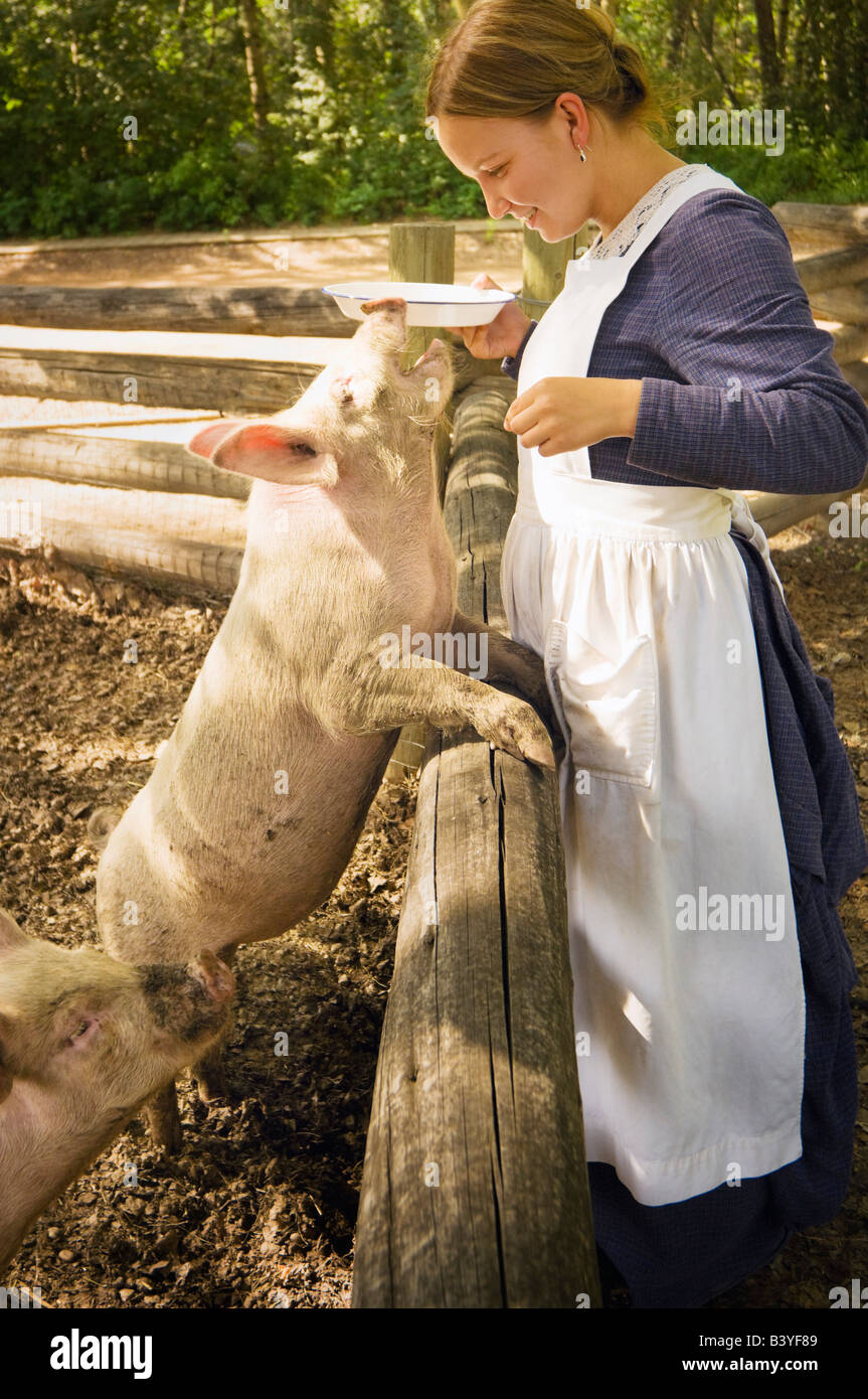 Donna che indossa il costume di Pioneer alimentazione di maiale, Fort Edmonton, Alberta, Canada Foto Stock