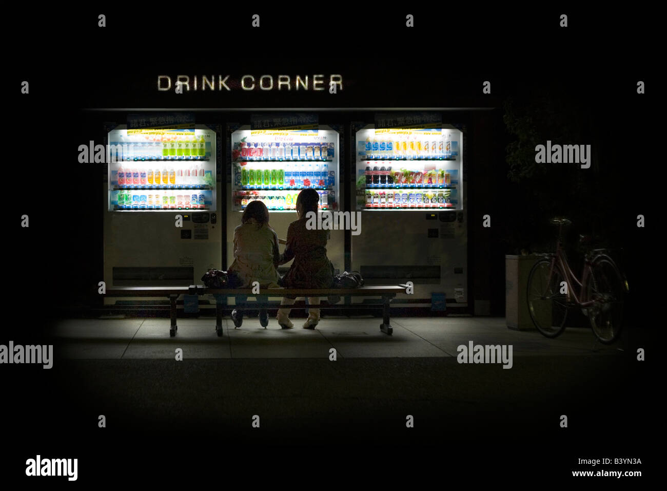 Distributori automatici di sera in Giappone con ragazze amiche sedute. Foto Stock