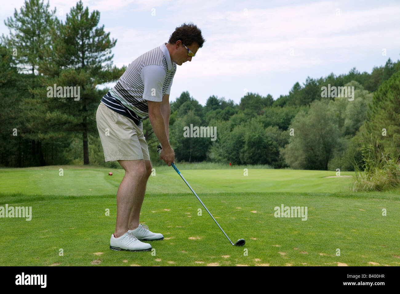 Il Golfer affrontare la sfera come egli sta per tee con un ferro da stiro su un corto par tre Foto Stock