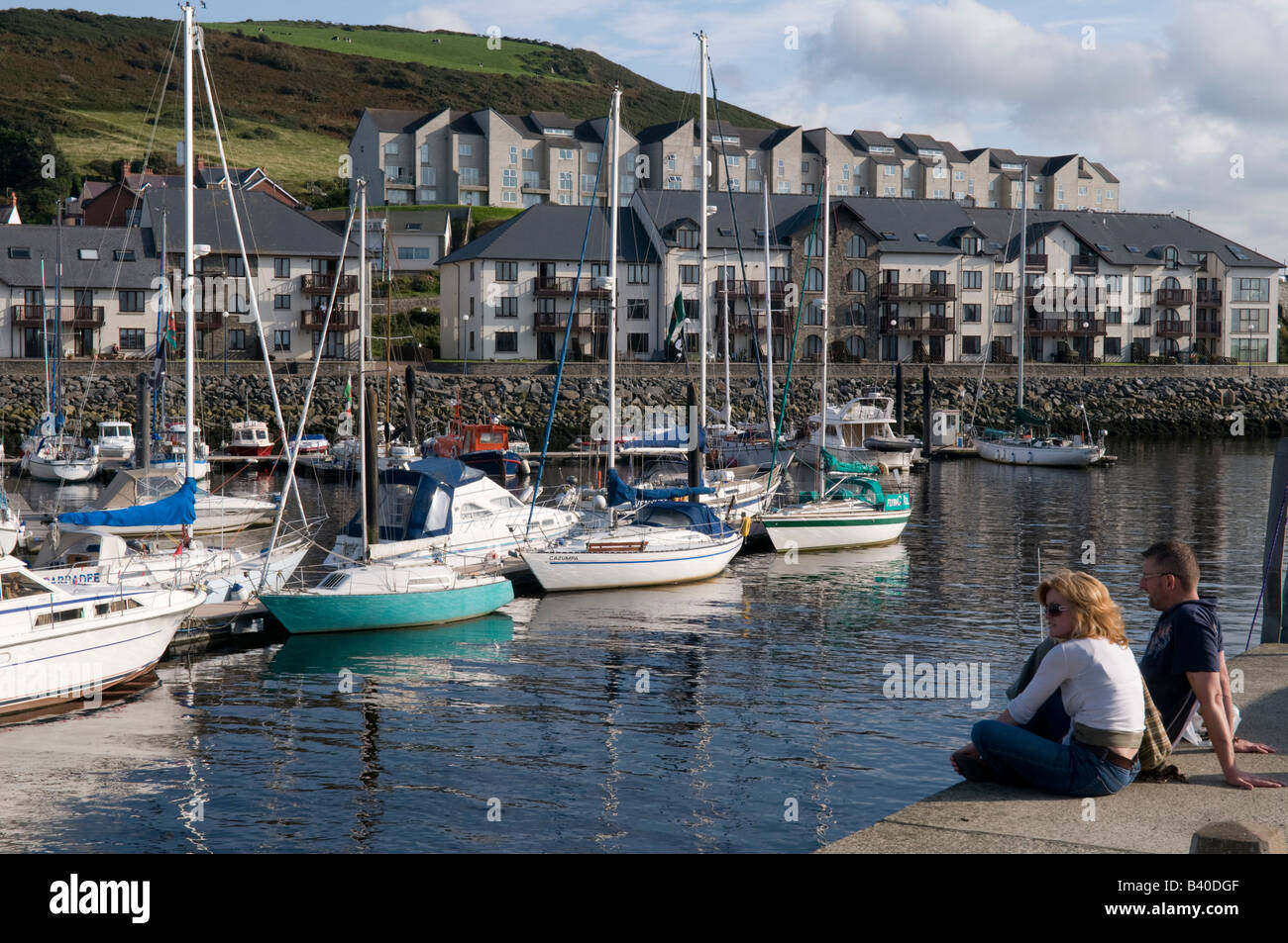 Giovane seduto sulla banchina a Aberystwyth porto e marina pomeriggio estivo Wales UK Foto Stock