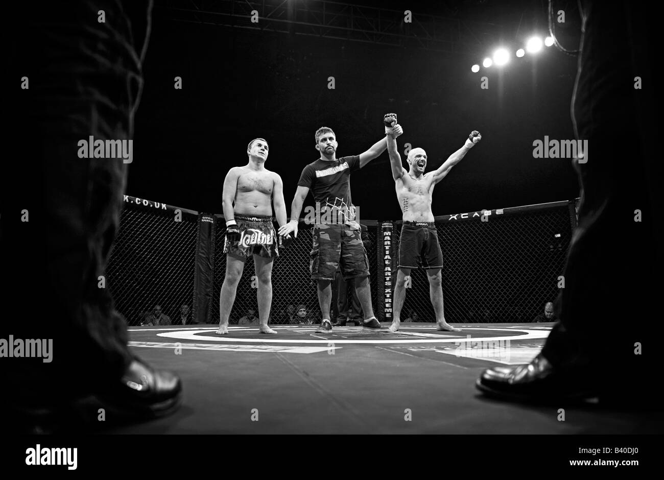 Arbitro detiene la gabbia vincente fighters mano aloft. Foto Stock