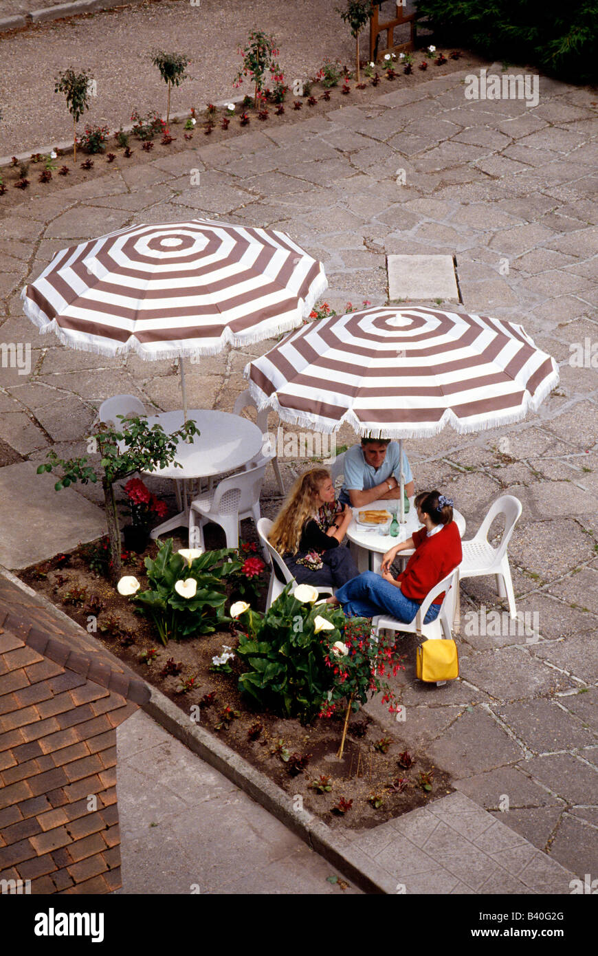Gli adolescenti in un outdoor cafe francese; Hostellerie de la Vieille Ferme, Mesnil Val Plage (Normandia), Francia Foto Stock