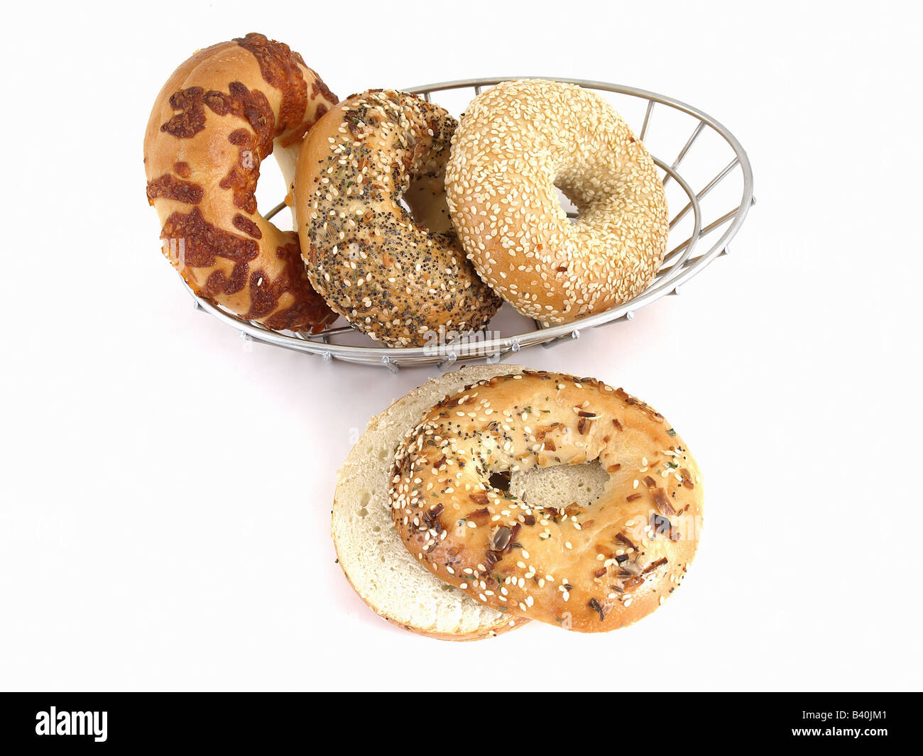 Freschi di forno bagel in un cesto in filo un bagel tutto affettato in primo piano isolati contro uno sfondo bianco Foto Stock