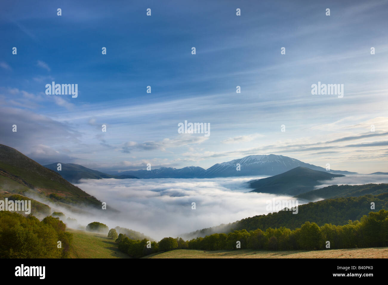 La nebbia giacente sul piano Grande all'alba con le montagne del Parco Nazionale dei Monti Sibillini che si eleva al di sopra, Umbria, Italia Foto Stock