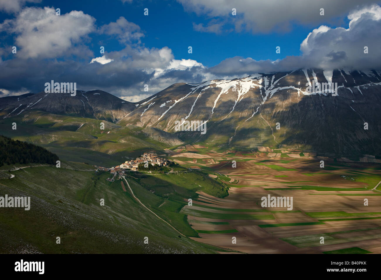 Il borgo di Castelluccio e il pianoforte Grande con le montagne del Parco Nazionale dei Monti Sibillini, Umbria, Italia Foto Stock