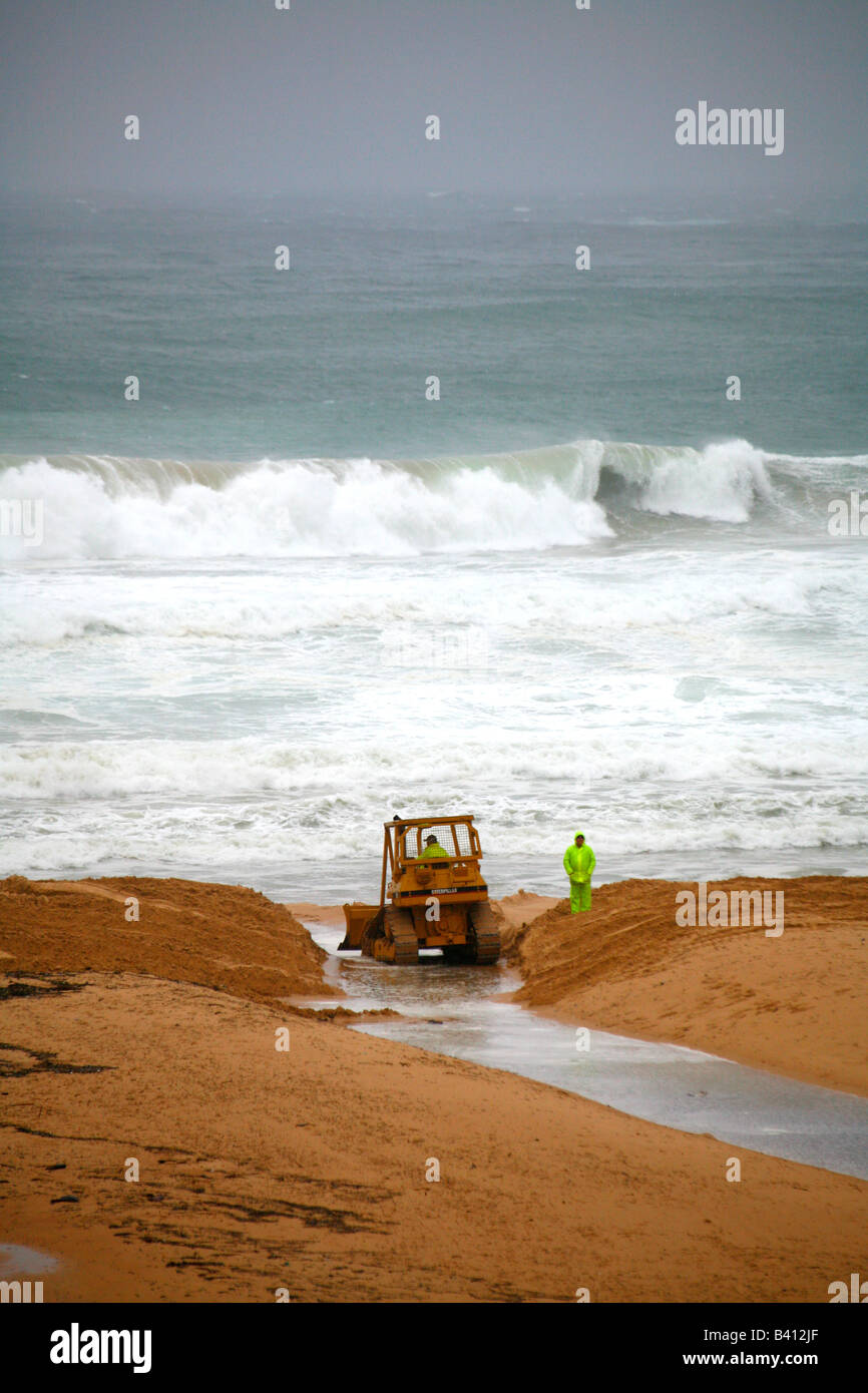 Macchine per movimento terra è utilizzato per rilasciare le acque di esondazione a Manly laguna Australia durante il ciclone meteo Foto Stock