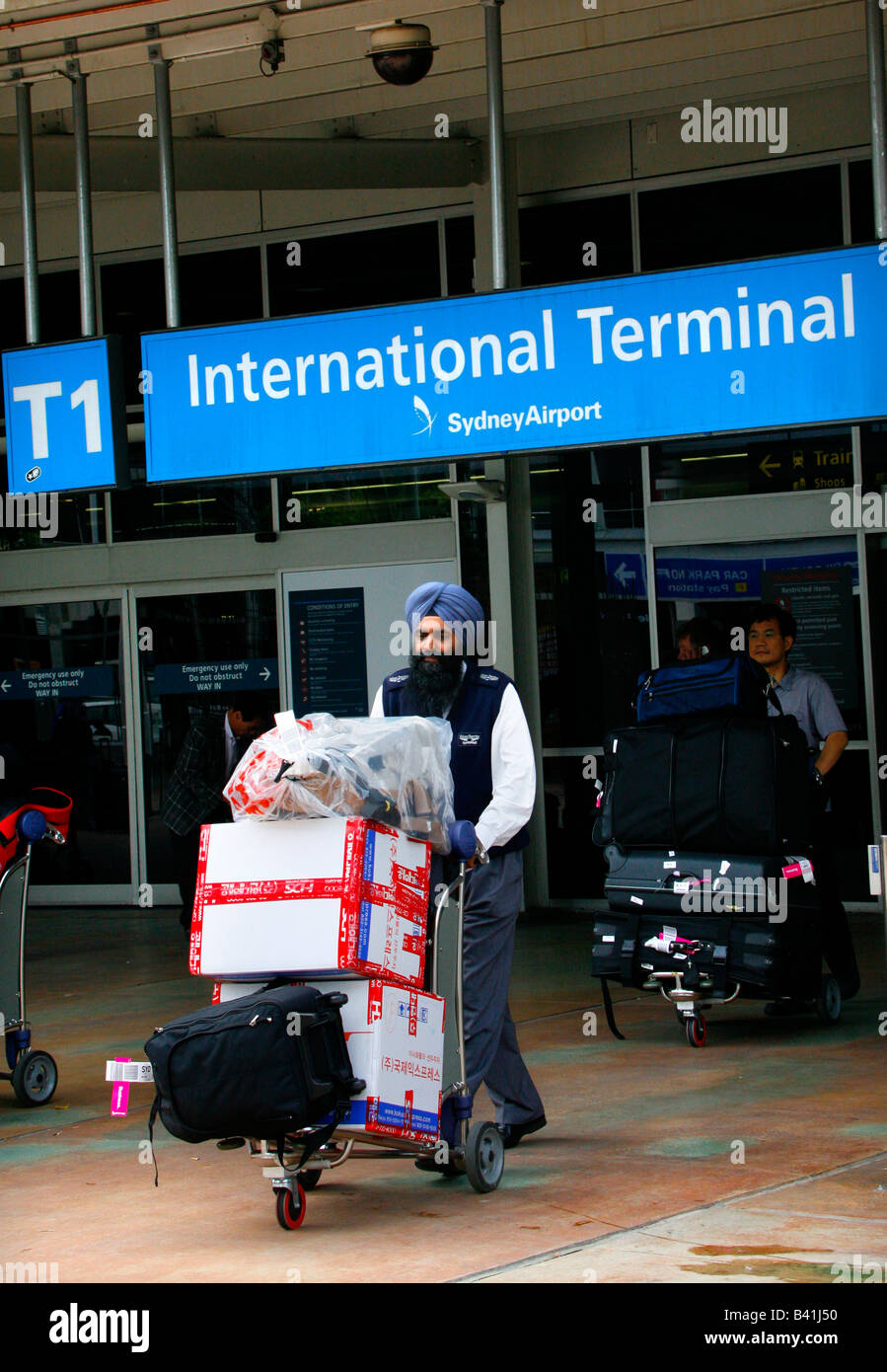 Un indiano Sihk Taxi driver ruote un bagaglio dei passeggeri dal Terminal Internazionale a Sydney s Mascot airport Foto Stock