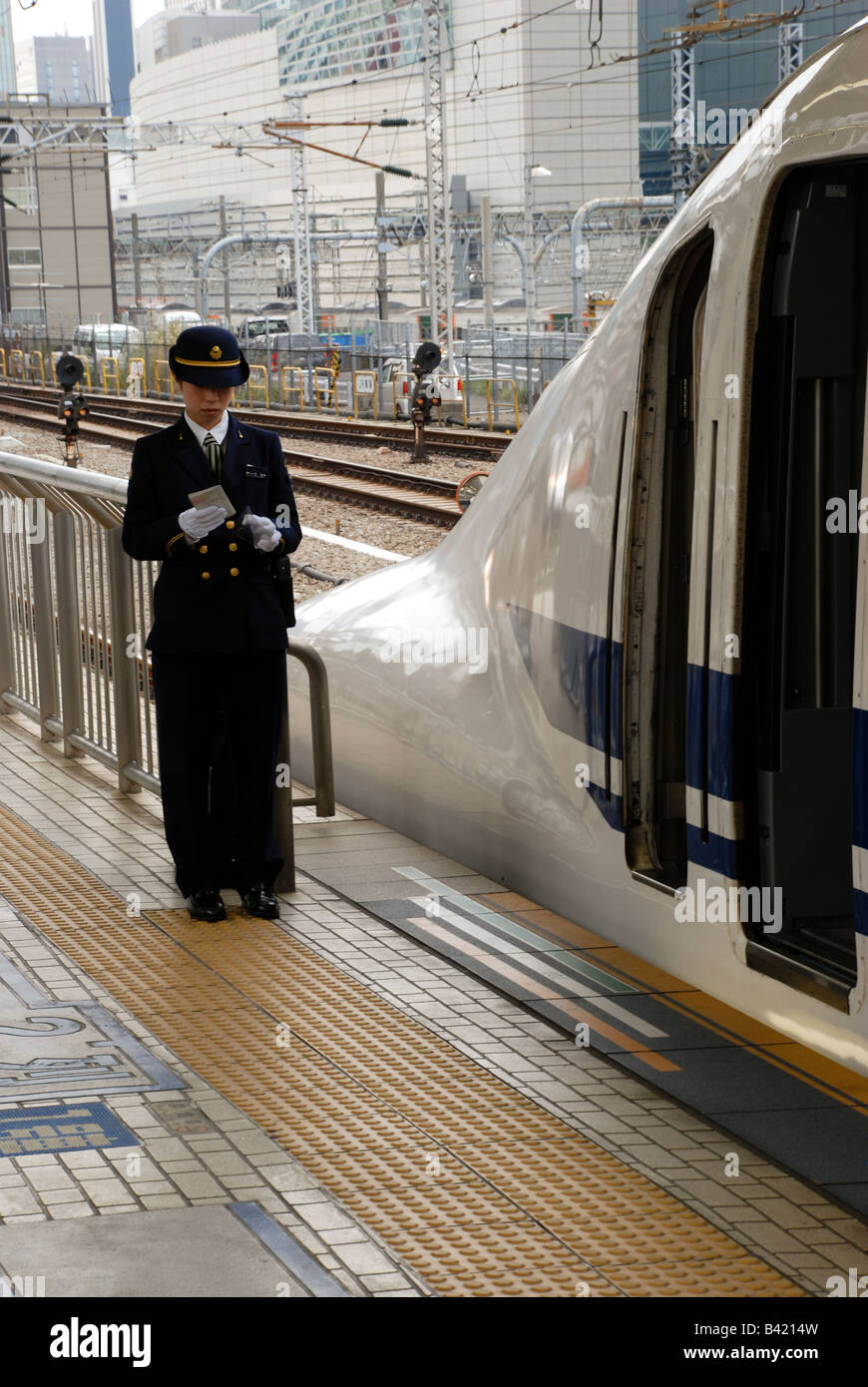 Treno femmina driver in controlli uniformi la sua pianificazione prima di entrare il treno superveloce Shinkansen alla stazione di Tokyo. Foto Stock