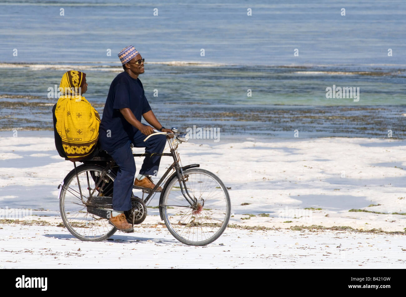 L'uomo e sua moglie in sella ad una bicicletta lungo la spiaggia di BWE Juu, Zanzibar Tanzania Foto Stock