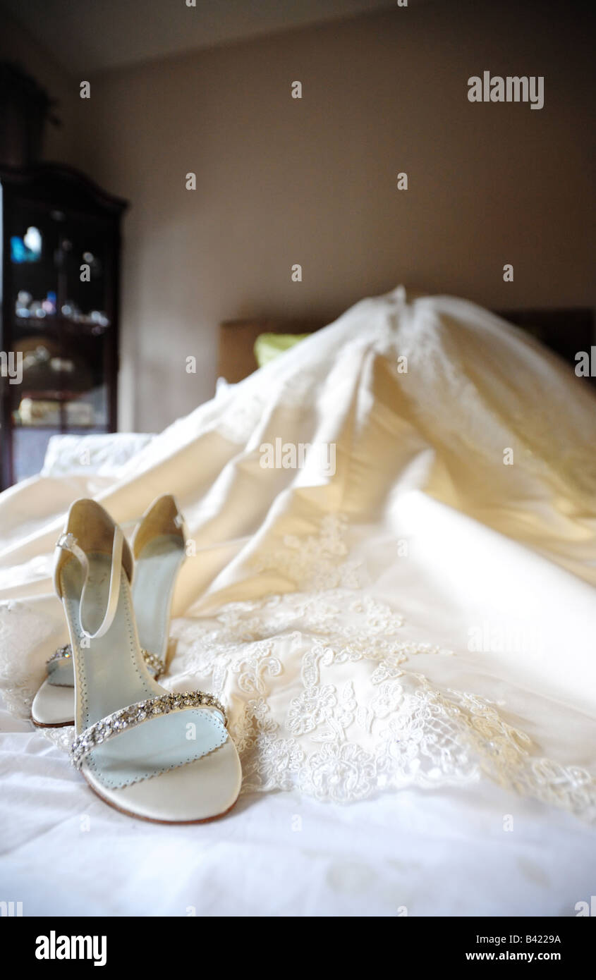 Abito da sposa e scarpe su un letto Foto Stock