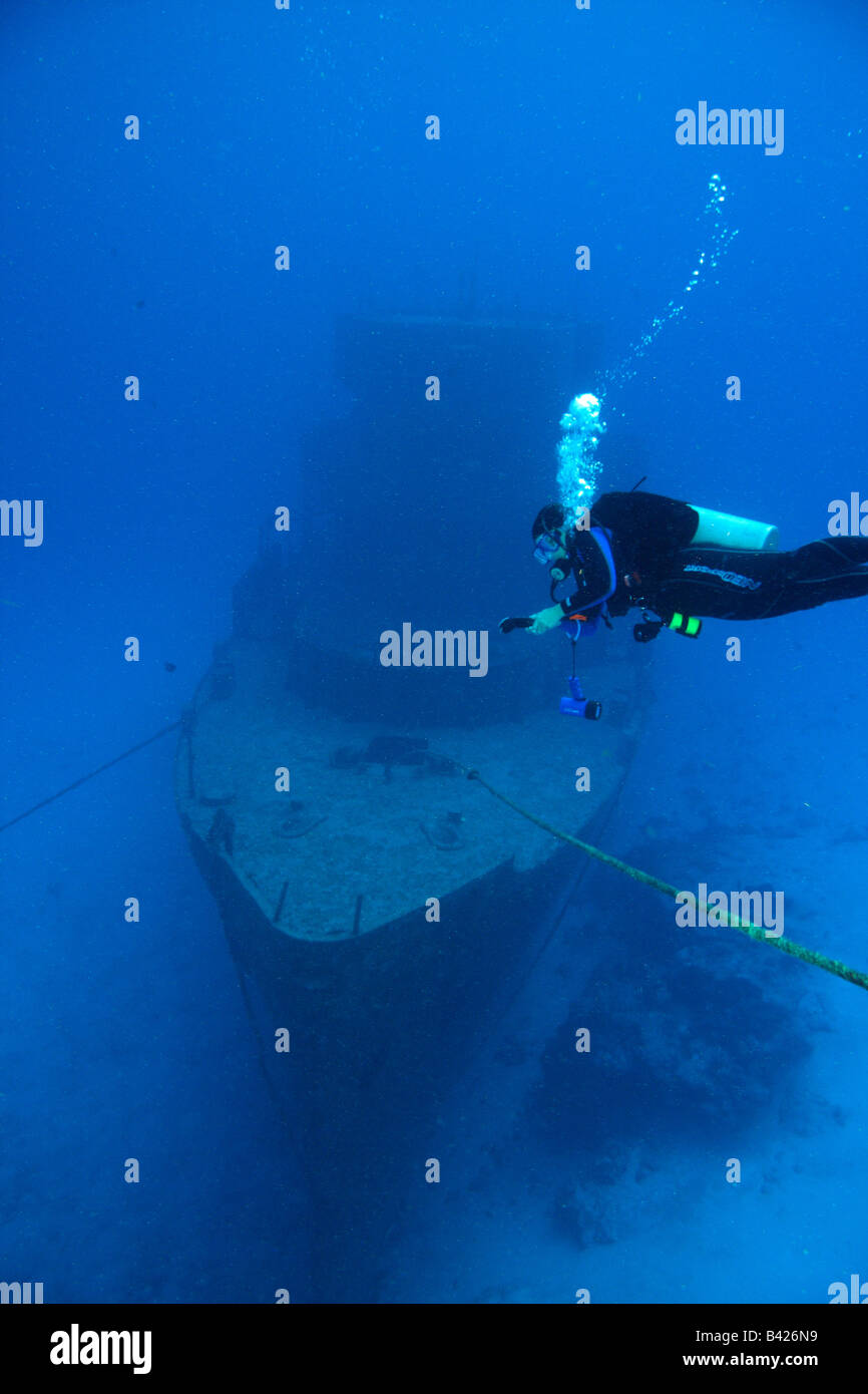 Un singolo subacqueo femmina di eseguire la decompressione di arresto di sicurezza con grande nave militare relitto in background. Foto Stock