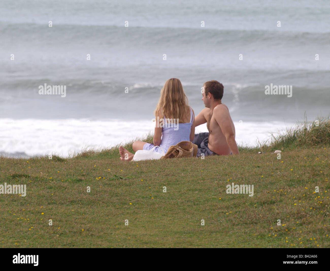 Giovane seduto sulla scogliera che guarda al mare Foto Stock