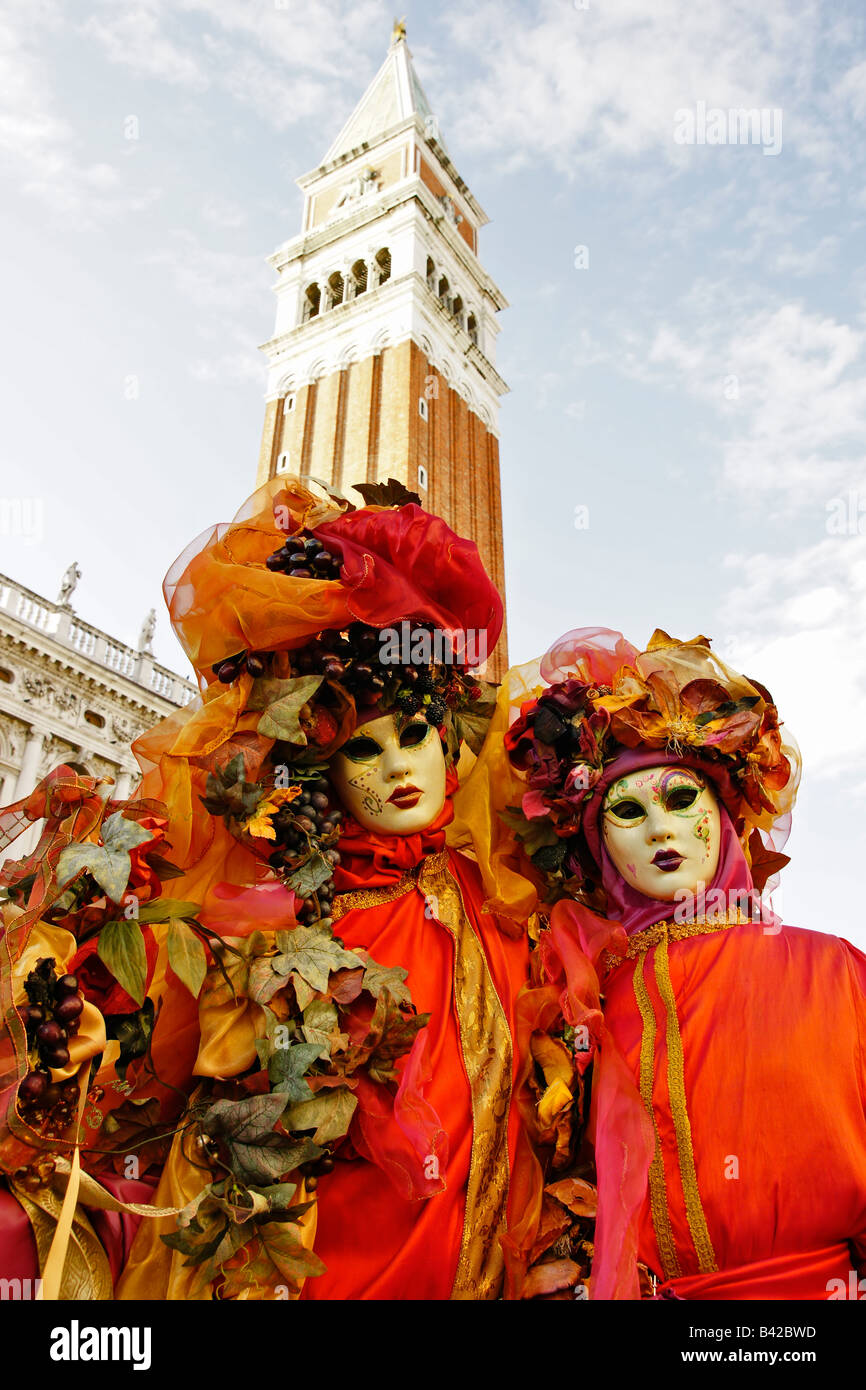 Uomo e donna in costume di carnevale rosso medievale, cappelli e maschere  in Piazza San Marco a Venezia con colonna di San Marco e colonna di San  Todar Foto stock - Alamy