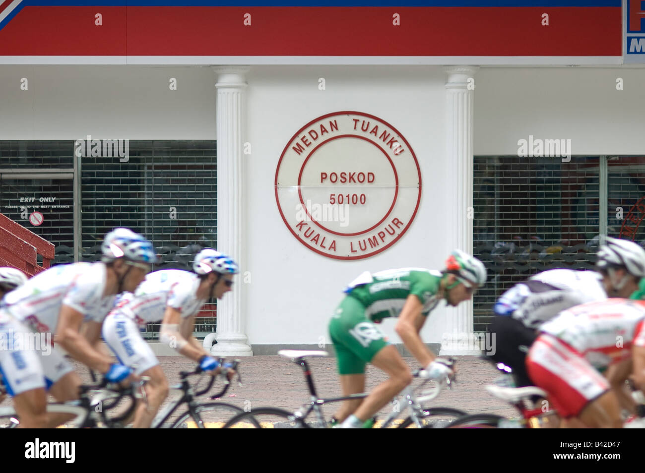 Ciclista racing passa una Malaysian Post Office Foto Stock