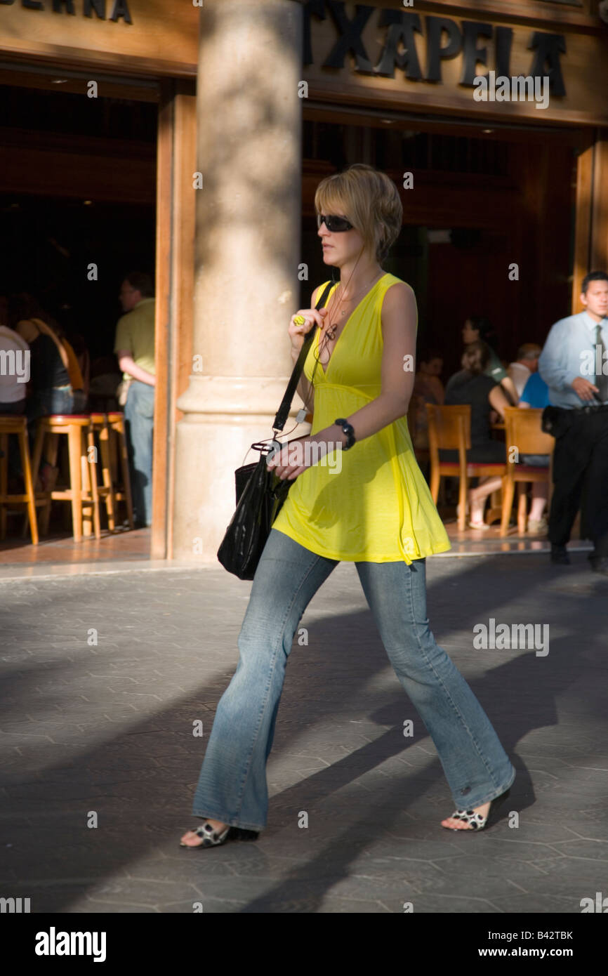 Donna attraente in abito giallo camminando sul Passeig de Gràcia nel quartiere di Eixample, strada trafficata in Barcellona, Spagna, Europa Foto Stock