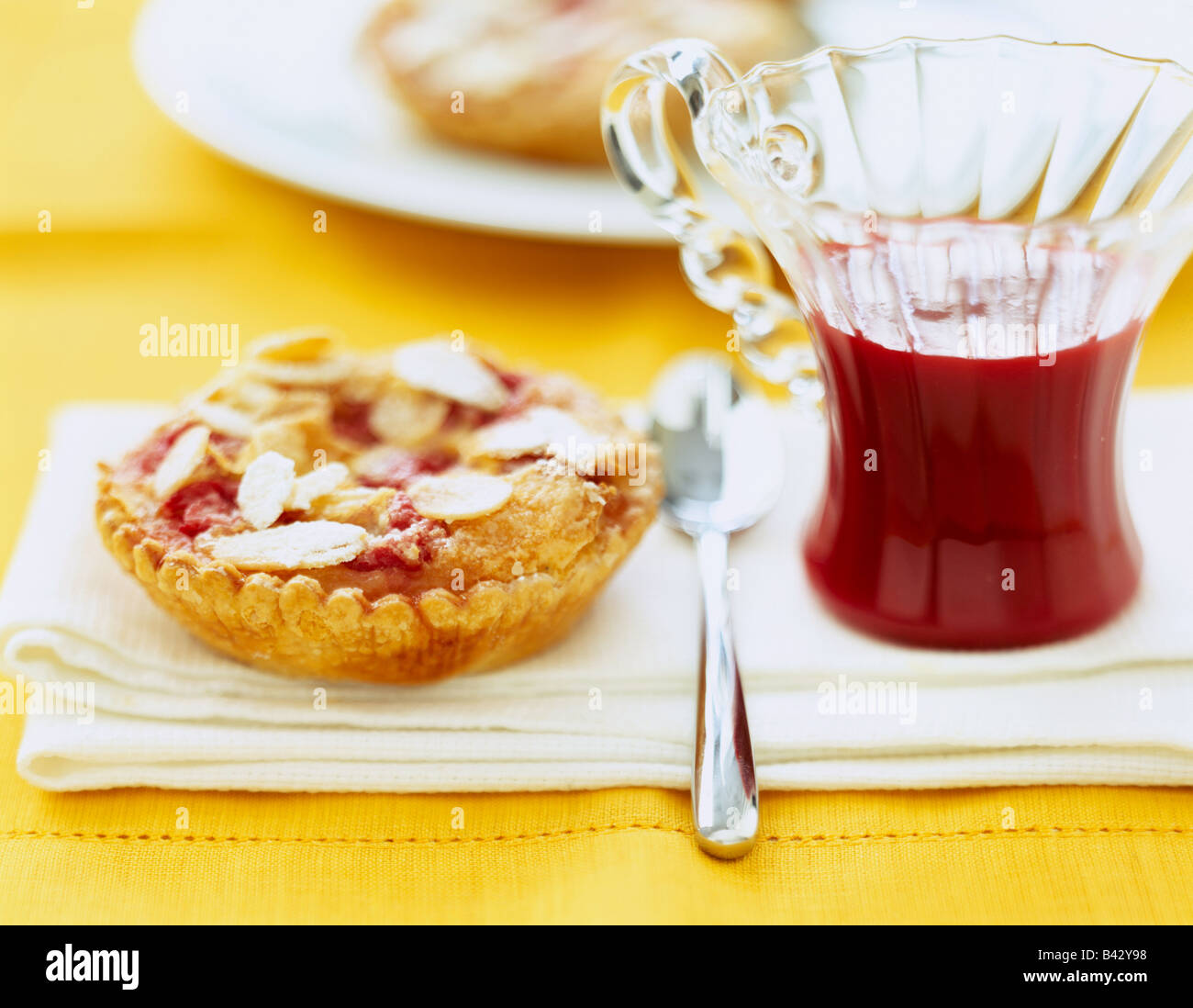 Mandorla,rosa pralina e banana tartlet con estate coulis di frutta Foto Stock