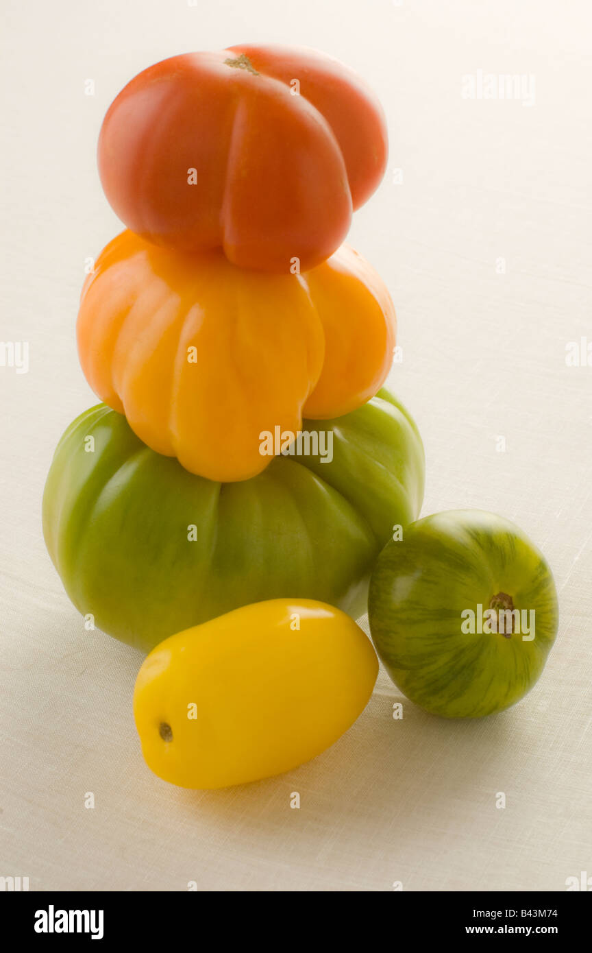 Una pila di cinque ripe rosso arancio giallo oro e verde cimelio di pomodori Foto Stock