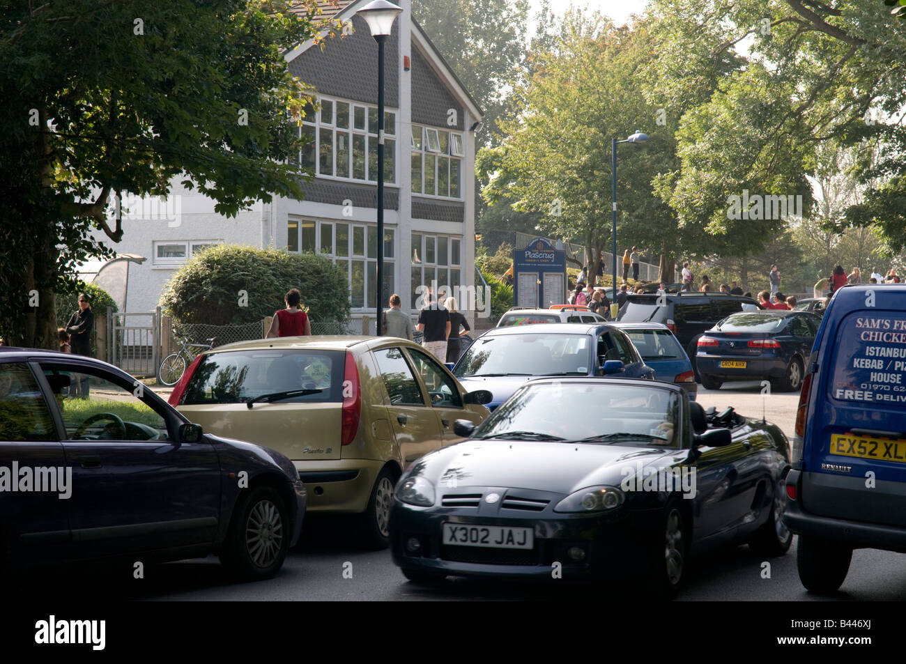 Code di auto - i genitori in attesa di raccogliere i bambini al di fuori Plascrug scuola primaria Aberystwyth Wales UK Foto Stock